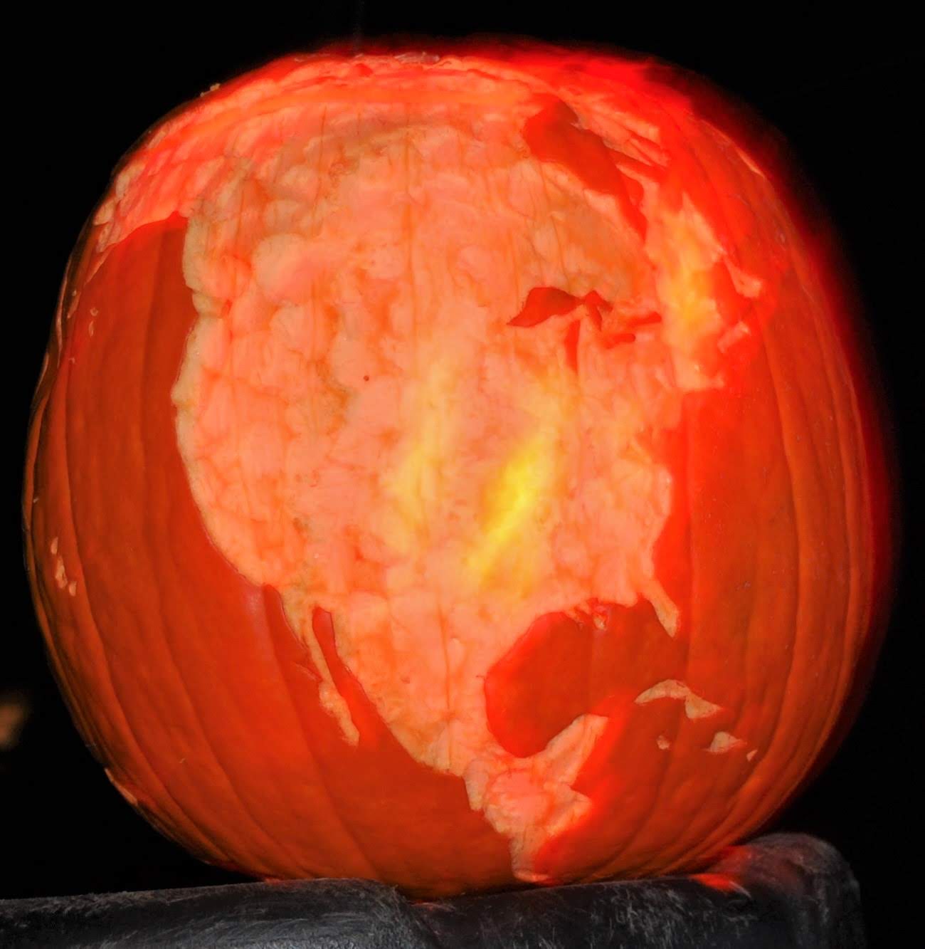 Pumpkin carved 2007 as the globe with land masses ablaze in orange glow, North America visible in this view.