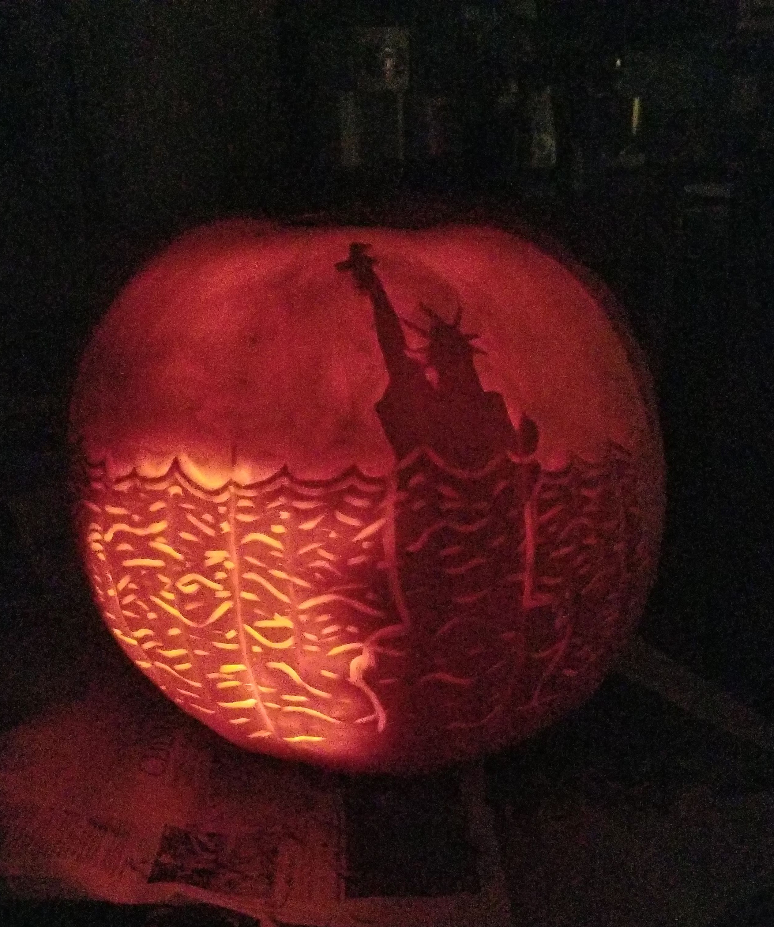 Pumpkin carved 2018 as the Statue of Liberty submerged, interior lit with a glow that doesn't quite resolve into a single source.